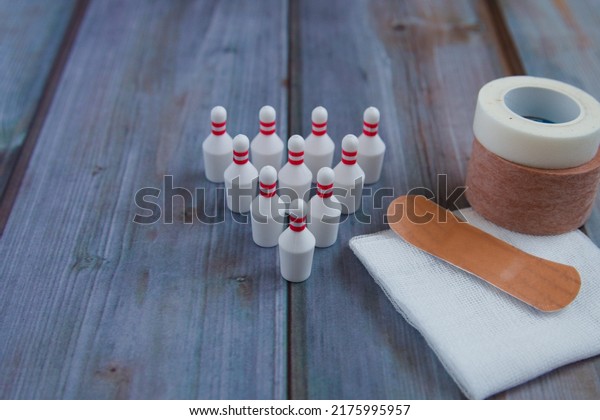 Bowling pin, surgical tape, gauze, adhesive\
plaster and wooden background to the\
right