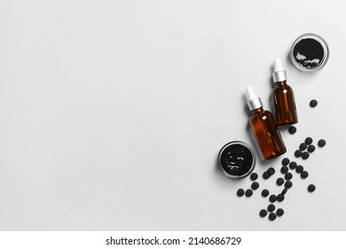 Bowls With Activated Carbon Mask, Pills And Bottles Of Essential Oil On White Background