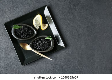 Bowls with black caviar on dark grey background
