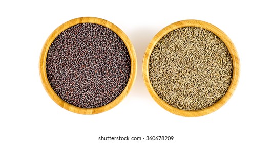 Bowls Of Black Mustard Seeds And Cumin Seeds In An Overhead Shot Against White Background.