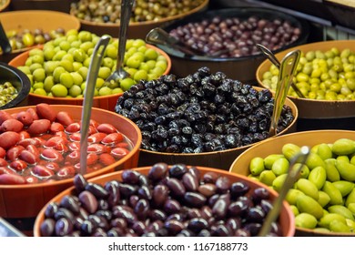 Bowls of green and black olives on display on a market stall