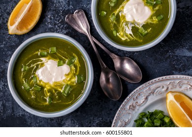 Bowls with green soup of broccoli, spinach and green pea, top view.