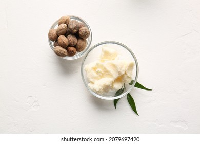 Bowls with shea butter and nuts on light background