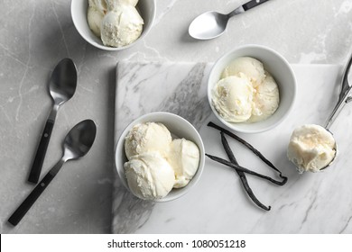 Bowls with tasty vanilla ice cream on marble board