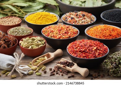 Bowls of various aromatic spices and culinary herbs. Different seasoning - red hot pepper, paprika, anise, saffron, black seeds, nutmegs, cardamom pods, thyme, gloves, curcuma. Condiments for cooking.
