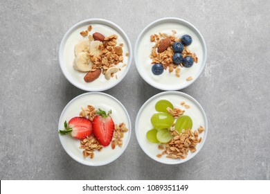 Bowls With Yogurt, Granola And Different Fruits On Gray Background, Top View