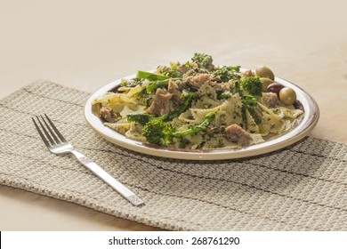 Bowtie Pesto Pasta With Ground Sausage And Broccoli Rabe Garnished With Fancy Olives