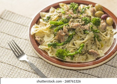 Bowtie Pesto Pasta With Ground Sausage And Broccoli Rabe Garnished With Fancy Olives