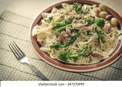 Bowtie Pesto Pasta With Ground Sausage And Broccoli Rabe Garnished With Fancy Olives