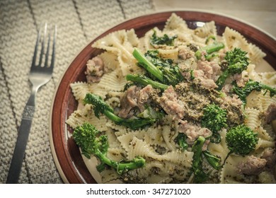 Bowtie Pesto Pasta With Ground Sausage And Broccoli Rabe Garnished With Fancy Olives