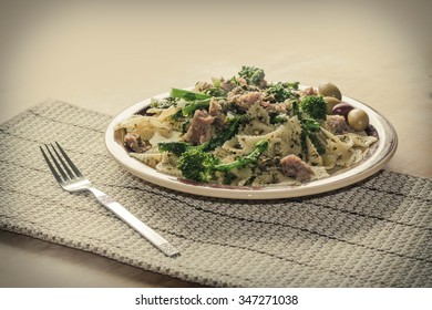 Bowtie Pesto Pasta With Ground Sausage And Broccoli Rabe Garnished With Fancy Olives