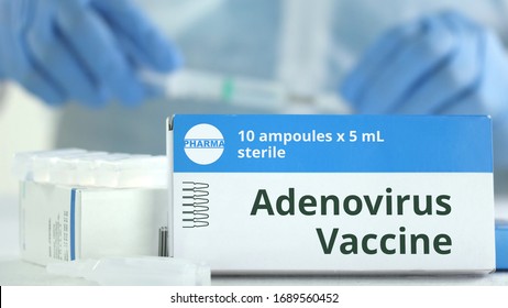 Box With Adenovirus Vaccine On The Table Against Blurred Lab Assistant Or Doctor. Fictional Phaceutical Logo