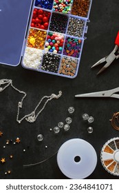 Box with colorful beads, string, wire, chain, scissors, pliers and hammer on dark background. Various jewelry making supplies. Top view. - Shutterstock ID 2364841071