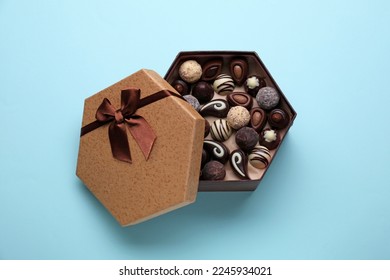 Box of delicious chocolate candies on light blue background, top view