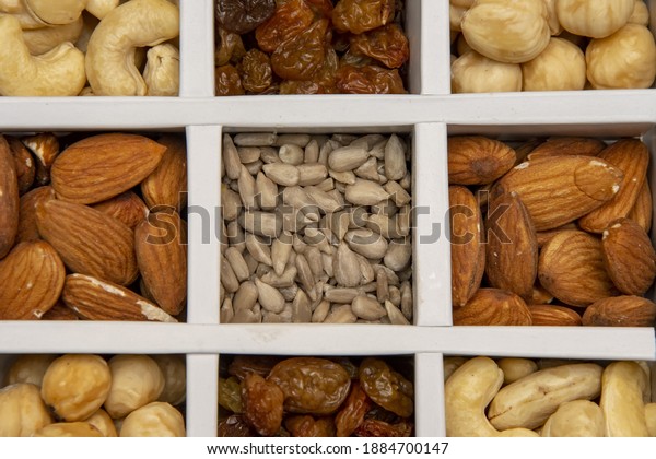 The box is divided into\
cashews, almonds, raisins and sunflower seeds, close-up, selective\
focus.