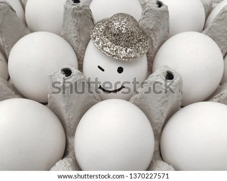 A box of eggs. Smiling egg in the hat.