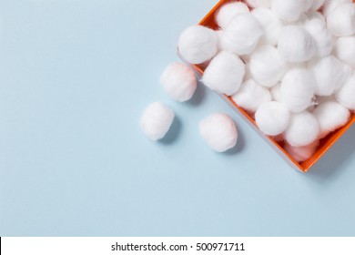 Box full of soft cotton balls on turquoise background, top view, copy space