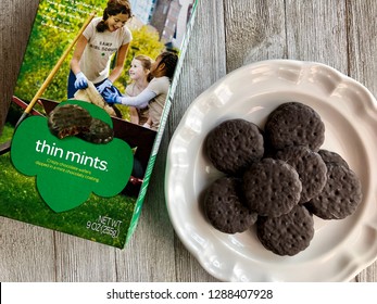 Box Of Girl Scout Thin Mints With A Few On A White Plate On A Wooden Surface