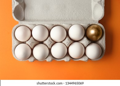 Box With Golden Egg Among White Ones On Color Background. Concept Of Uniqueness