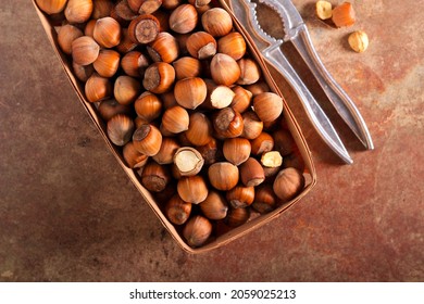 Box with hazelnuts and nutcracker over stone table