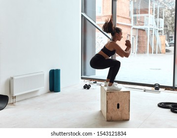 Box Jumping At Crossfit Style In Gym, Box Jump Performing Of Young Fit Girl. Window Background