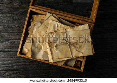 Box with old letters on wooden background, top view