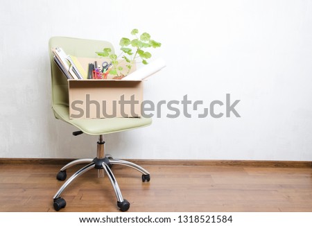 Box with personal items standing on the chair in the office.Concept of moving or dismissal