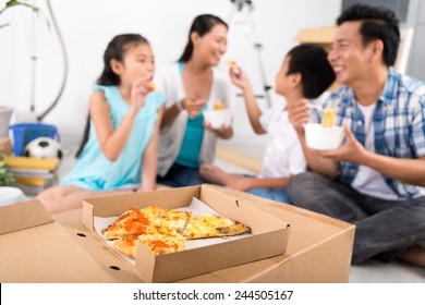 Box Of Pizza On The Background Of Family Eating At Home