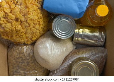 Box Of Products: Oil, Rice, Pasta, Canned Food, Cornflakes. Food Help  To Schoolchildren. Top View. Close Up