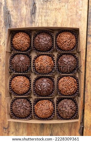 Box with several brigadeiros lined up on wooden table. Brazilian traditional sweet.