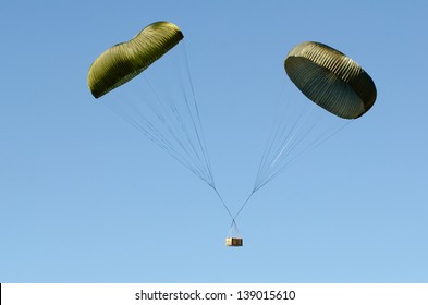 A Box Suspended Beneath Two Parachutes During A Military Air Drop