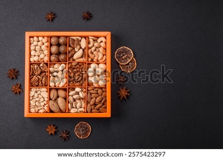 Box with various nuts cashew, macadamia, peanut, cedar, pecan, walnut, brazil, hazelnut on dark textured background