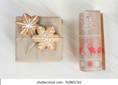Box wrapped in brown craft paper scandinavian style with ginger cookies and paper roll aside