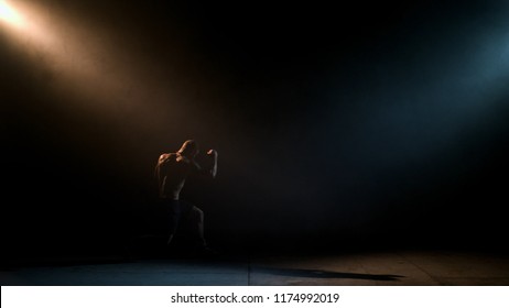 Boxer doing shadow Boxing in a dark room. Man of athletic build makes a punch. Dramatic lighting - Powered by Shutterstock