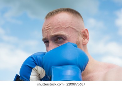 Boxer In A Fight. Fist Fight. Strong Man Strong Body Boxing Outdoor. Man With Muscular Body And Bare Torso With Boxing Punch Gloves. Man Face Close Up In Boxing.