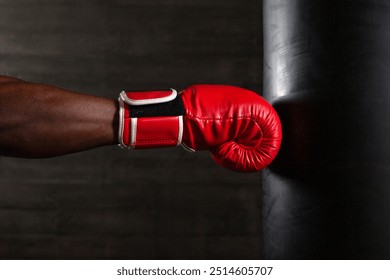 boxer hand in red glove hitting punching bag on black background, african american athlete training punch, close up - Powered by Shutterstock