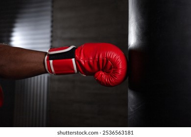 boxer hand in red glove hitting punching bag on black background, african american athlete training punch, close up - Powered by Shutterstock