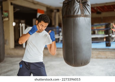 un boxeador golpeando seriamente las bolsas pesadas en el estudio de boxeo