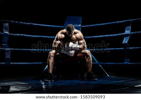 boxer sitting and recreation on boxing ring, black background, horizontal photo