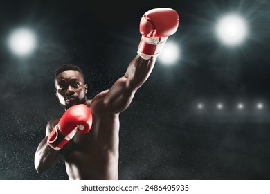 A boxer throws a punch in a boxing ring, under the spotlight. - Powered by Shutterstock