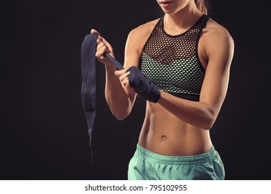 Boxer woman applying wrist wraps on black background - Powered by Shutterstock