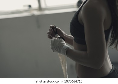 Boxer woman wrapping her wrists and hands with protective bandage, she is training at the boxing club - Powered by Shutterstock