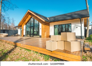 boxes with things for moving on the background of a new house. concept of moving to a new home