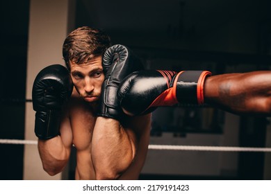 Boxing Athlete Blocking A Punch To His Jaw During A Match With His Opponent. Two Male Boxers Fighting In A Boxing Ring.