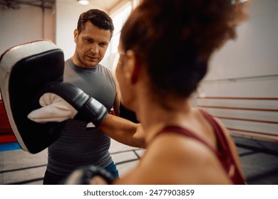 Boxing coach having sports training with female fighter in health club.  - Powered by Shutterstock