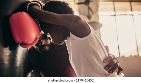 Boxing coach talking to a tired kid. Boxing kid relaxing after practice at a boxing gym. - Powered by Shutterstock