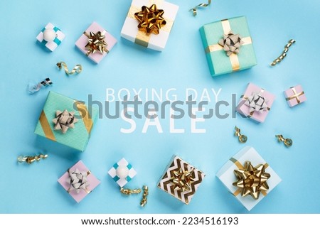 Boxing Day Sale promotion composition background. Christmas Shopping, Offer, Sale Concept. Holiday decorations and festive gift boxes on pastel blue background. Flat lay, top view, copy space. 