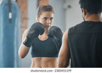 Boxing, exercise and training with a female boxer exercising with her fitness coach or personal trainer in the gym. Fighting, self defense and combat sport with a young woman and her workout partner - Powered by Shutterstock