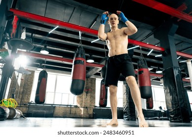 in a boxing fight club bald young boxer with tattoos in blue bandages trains a kick before a fight professional training fighting technique training - Powered by Shutterstock