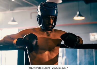 Boxing fighter with head guard posing, caucasian boxer punch his fist in front of camera in aggressive stance and ready to fight at the boxing match ring. Impetus - Powered by Shutterstock